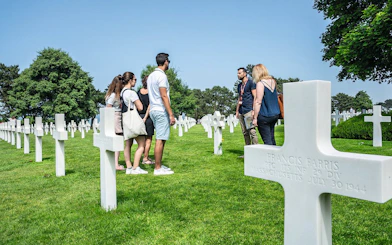 Group tour at Normandy American Cemetery with guide among white crosses.