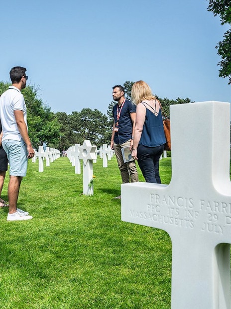 Group tour at Normandy American Cemetery with guide among white crosses.