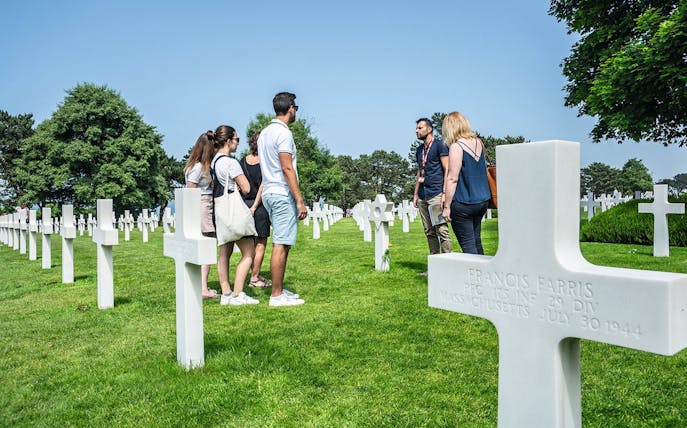 Group tour at Normandy American Cemetery with guide among white crosses.