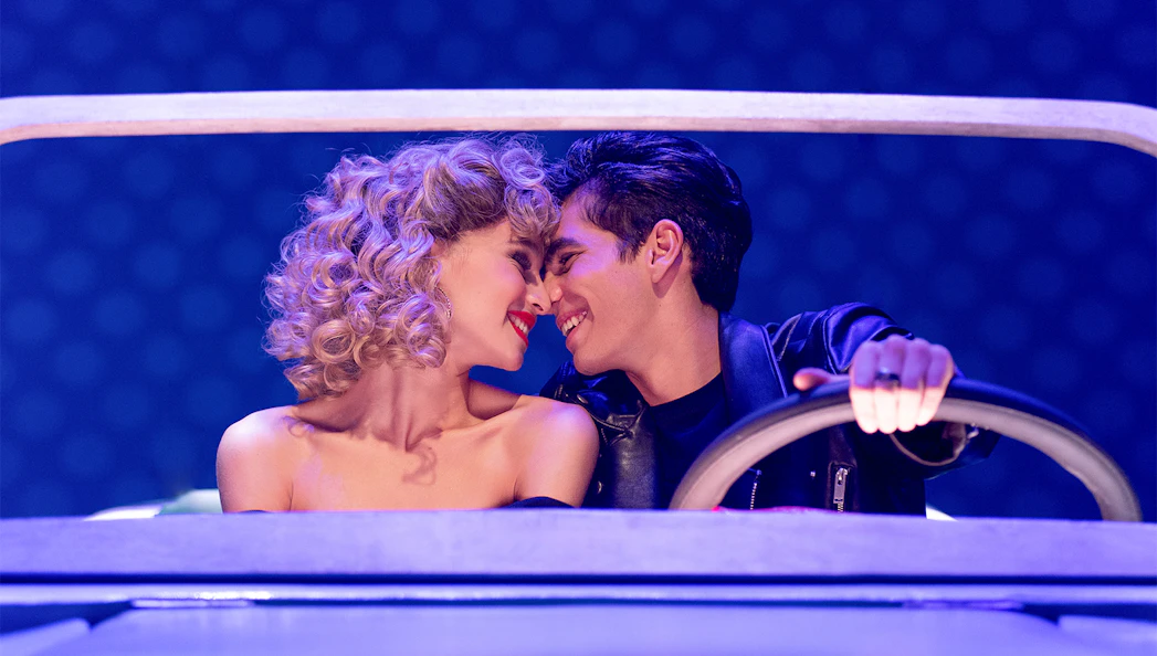 Couple in a car scene from the musical Grease.