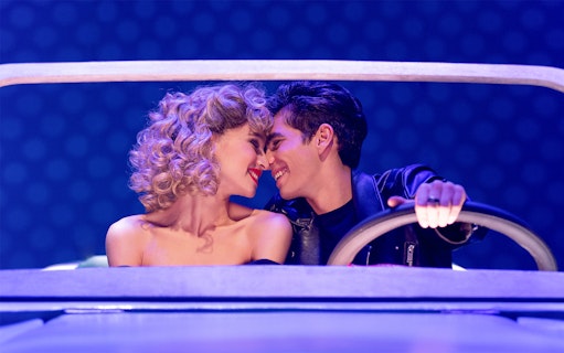 Couple in a car scene from the musical Grease.