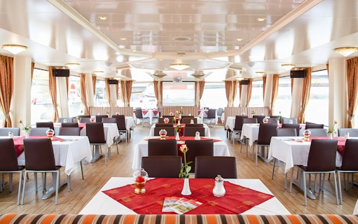 Interior of a Vienna sightseeing cruise ship with dining tables and large windows.
