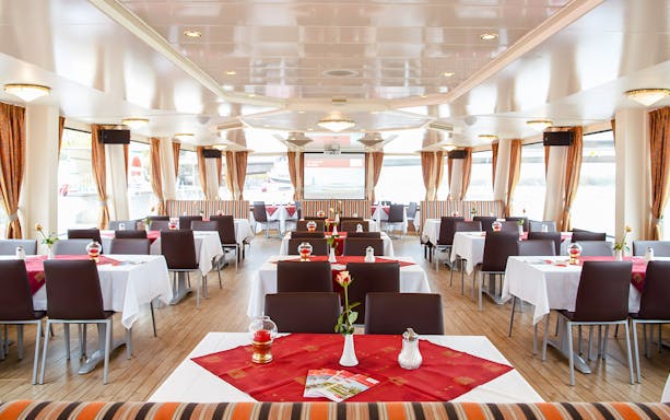 Interior of a Vienna sightseeing cruise ship with dining tables and large windows.