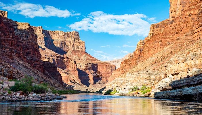 Colorado River flowing through the Grand Canyon with towering red rock cliffs.