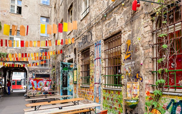 Colorful graffiti and hanging flags in a Berlin courtyard, part of the Guided Bike Tour: Vibes of Berlin.