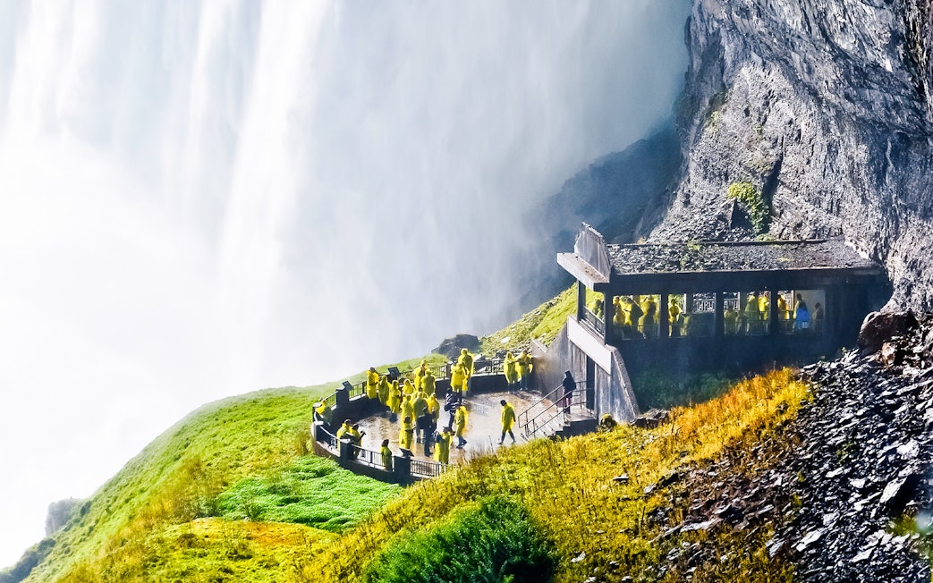 Visitors in yellow ponchos on the Journey Behind the Falls deck at Niagara Falls.
