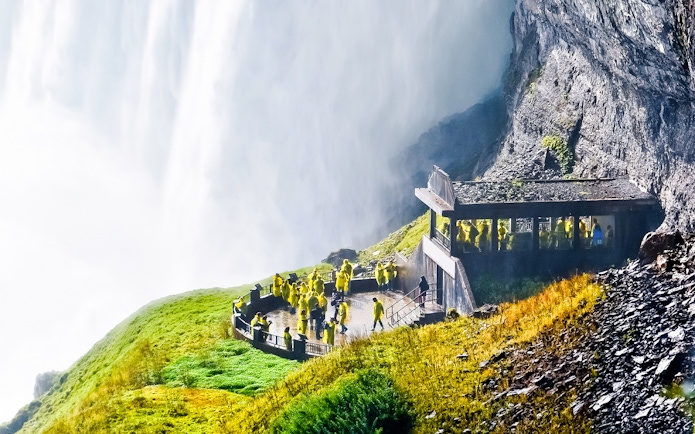 Visitors in yellow ponchos on the Journey Behind the Falls deck at Niagara Falls.