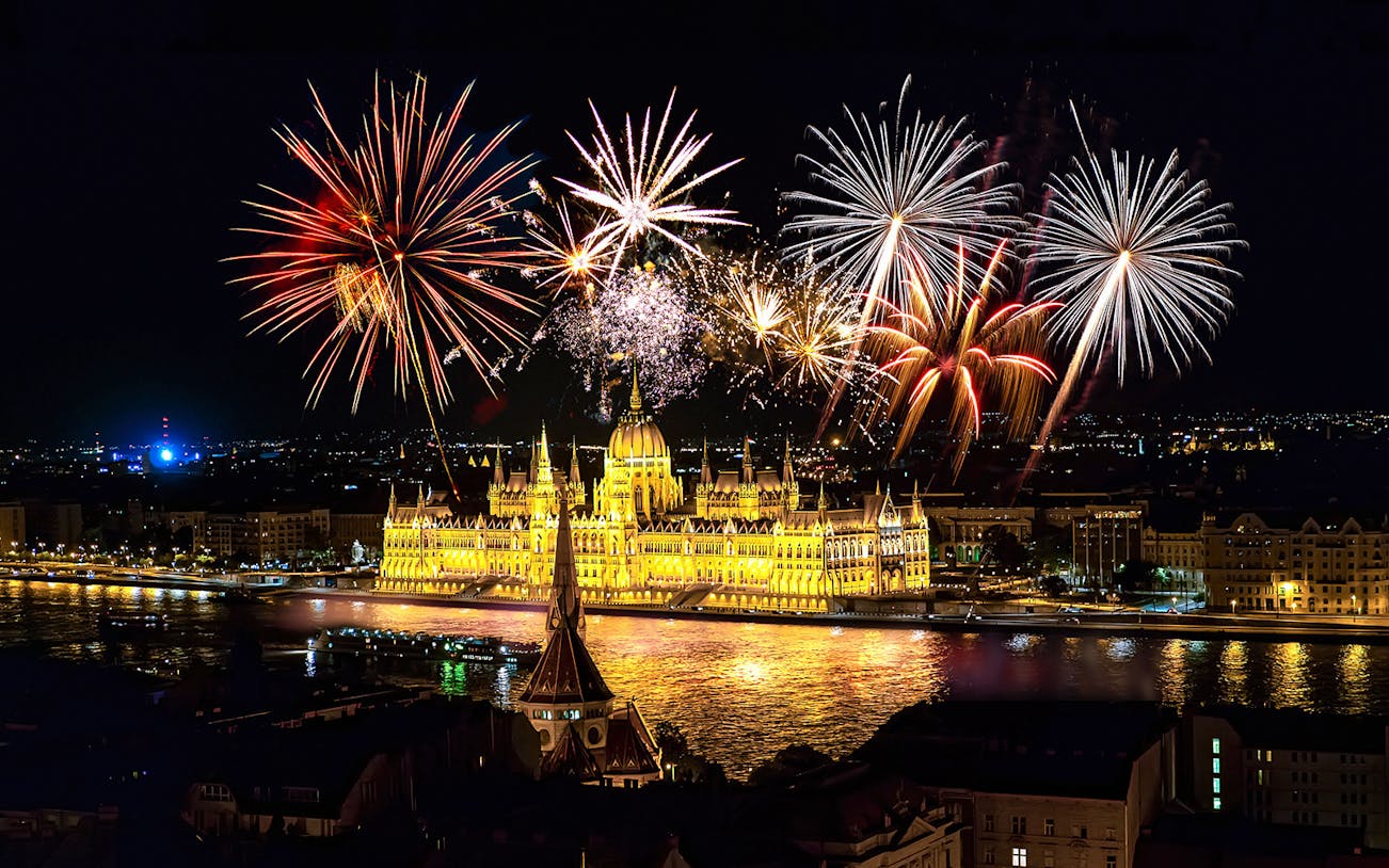 Budapest fireworks over the illuminated Parliament building during a river cruise.