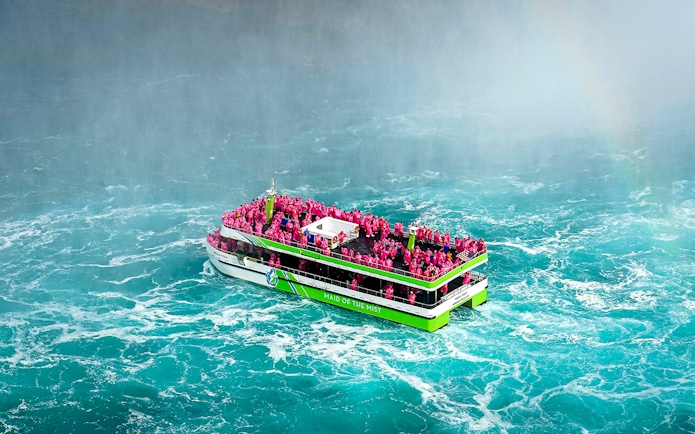 Maid of the Mist boat with passengers in pink ponchos near Niagara Falls.