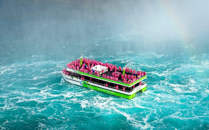 Maid of the Mist boat with passengers in pink ponchos near Niagara Falls.