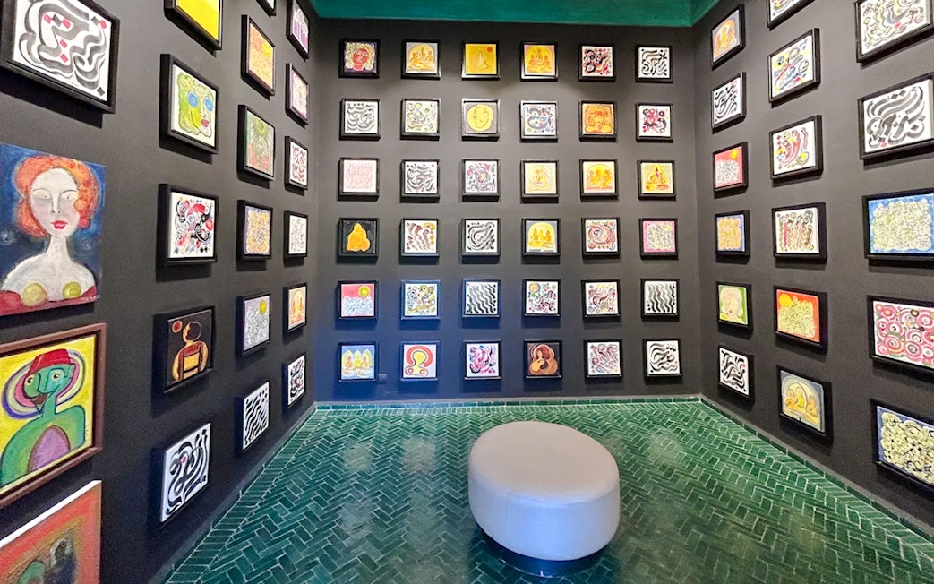 Art gallery inside Le Jardin Secret, Marrakech, featuring colorful abstract paintings on black walls.