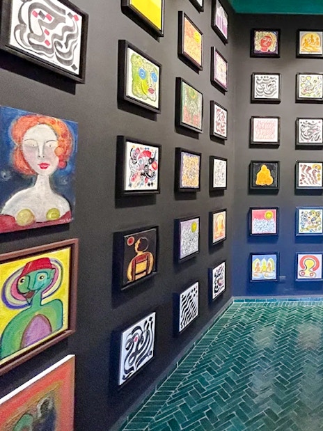 Art gallery inside Le Jardin Secret, Marrakech, featuring colorful abstract paintings on black walls.