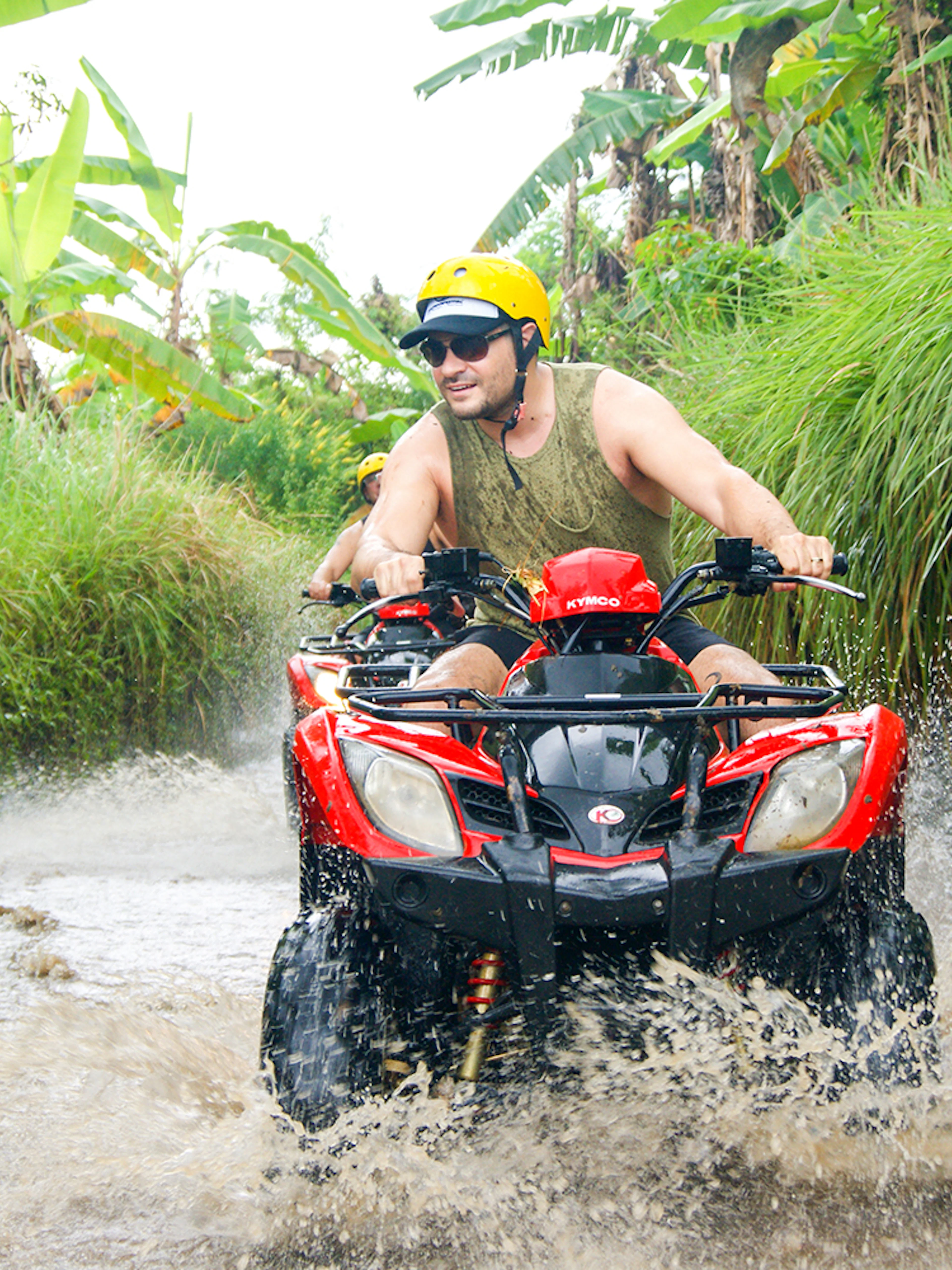 ATV rider navigating a muddy trail in Bali jungle during guided tour.