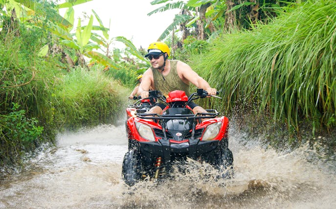 ATV rider navigating a muddy trail in Bali jungle during guided tour.