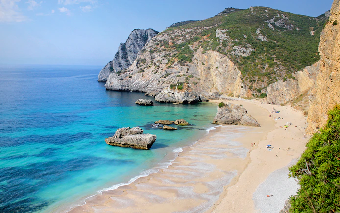 Ribeira do Cavalo Beach with cliffs and clear water, part of a guided snorkeling tour from Lisbon.