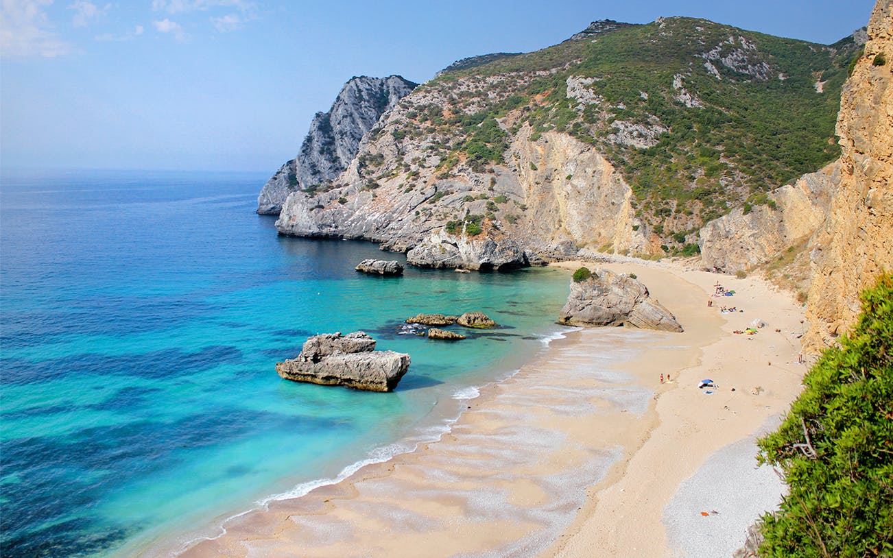 Ribeira do Cavalo Beach with cliffs and clear water, part of a guided snorkeling tour from Lisbon.