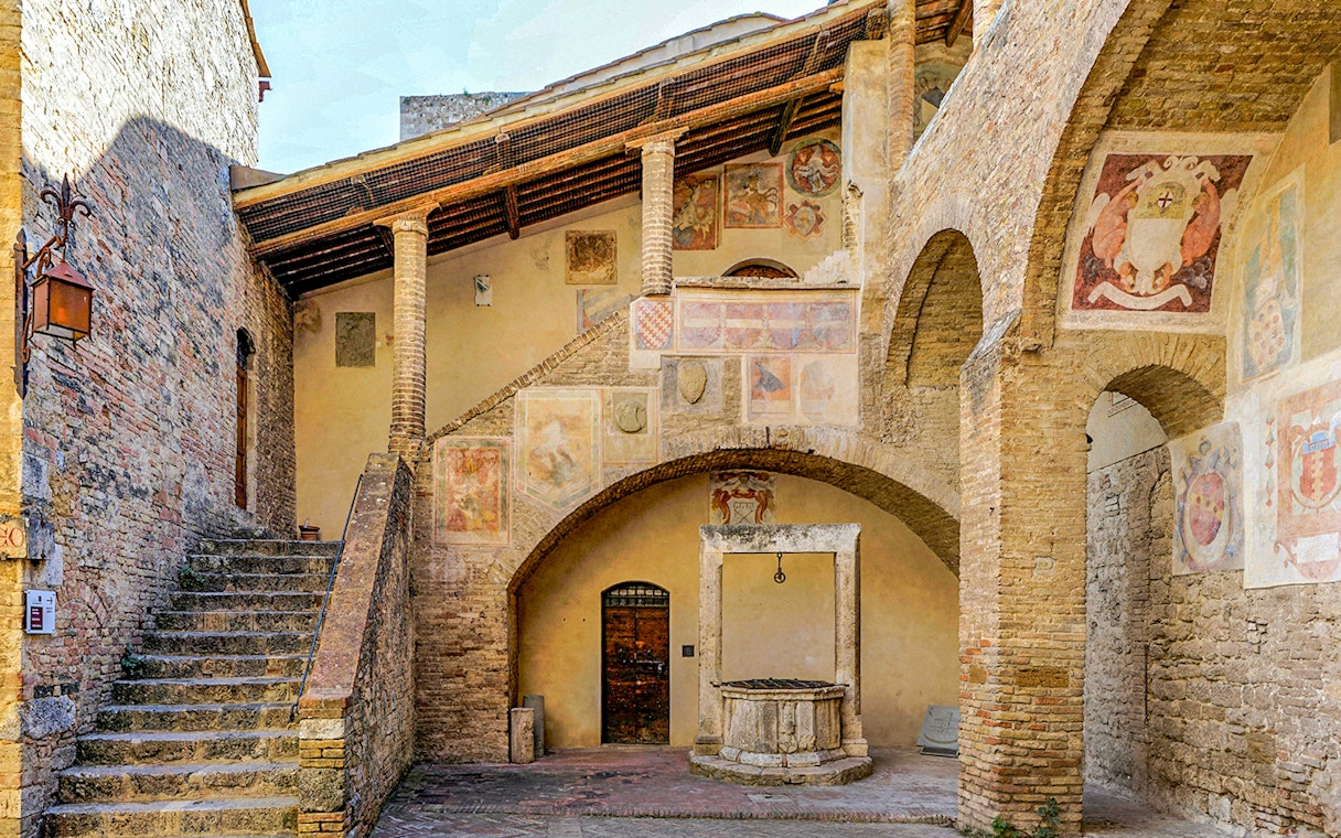 Volterra courtyard with frescoes and stone well, part of Combo: Volterra Pass + San Gimignano Pass + San Pietro Museum.