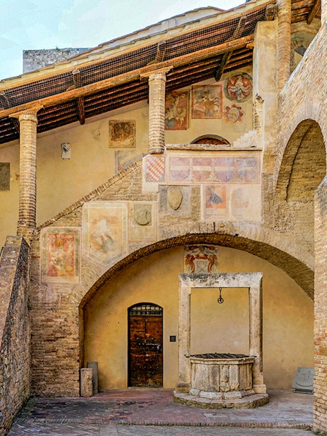 Volterra courtyard with frescoes and stone well, part of Combo: Volterra Pass + San Gimignano Pass + San Pietro Museum.