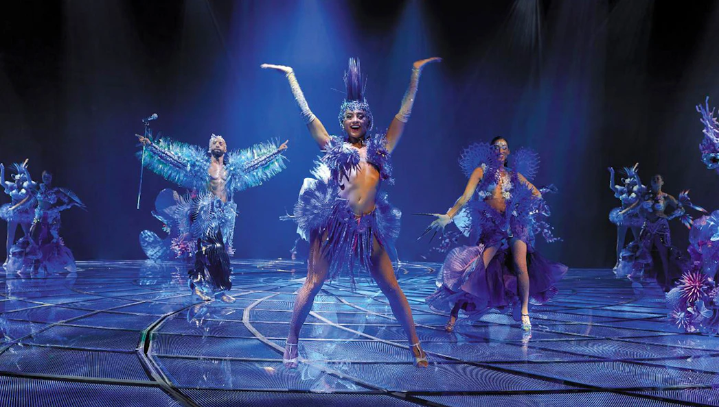 Performers in vibrant costumes on stage during the "Awakening" show.