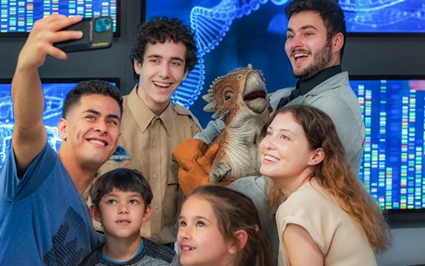 Visitors taking a selfie with a dinosaur puppet at Jurassic World: The Exhibition in Melbourne.