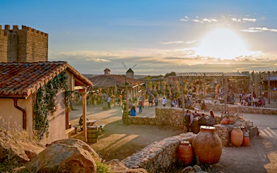 Puy du Fou España park village scene with visitors and sunset.
