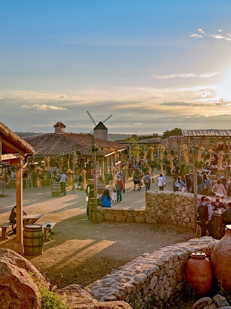 Puy du Fou España park village scene with visitors and sunset.