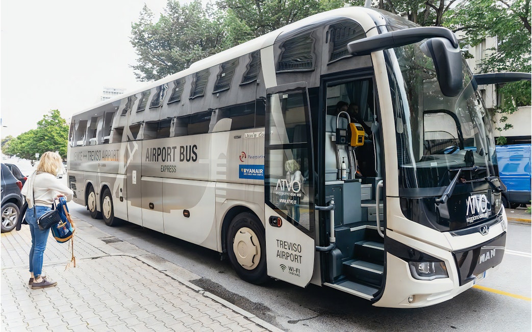 Airport bus for transfer from Venice Marco Polo, parked with a passenger nearby.