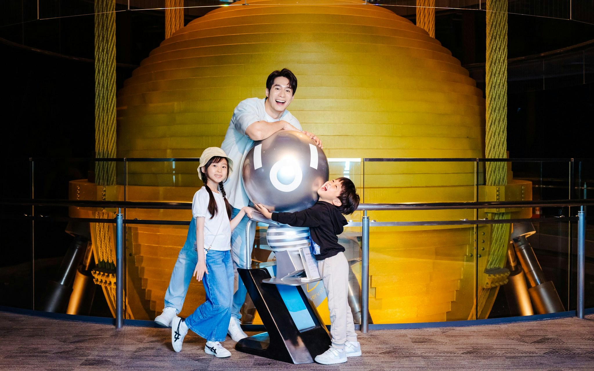 Family posing with the Taipei 101 damper ball exhibit.