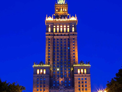 Palace of Culture and Science illuminated at night in Warsaw, Poland.