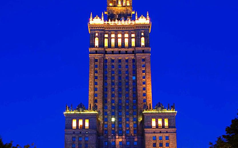 Palace of Culture and Science illuminated at night in Warsaw, Poland.