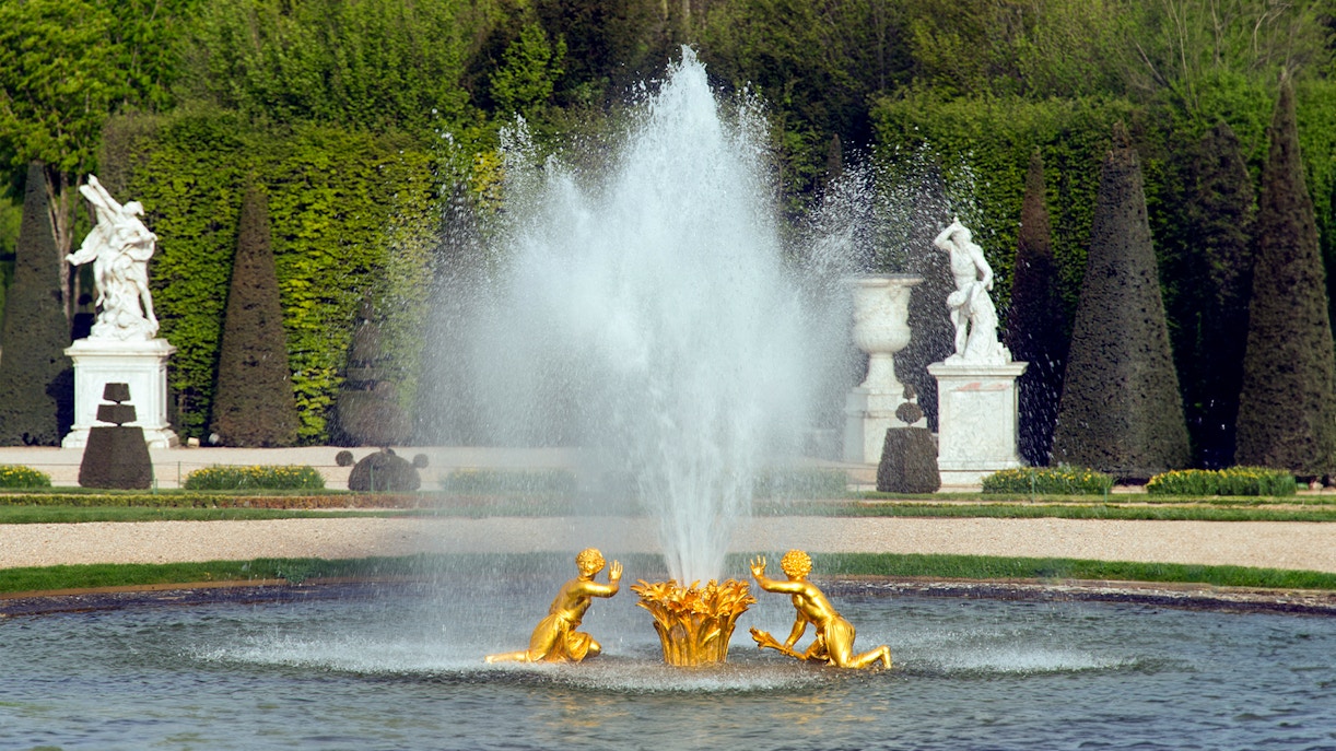 Fountain with golden statues at Palace of Versailles gardens, France.