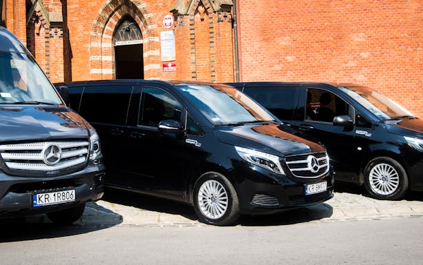 Mercedes vans parked outside a brick building for Krakow-Balice Airport transfer.