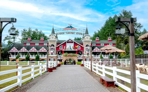 Entrance to Dairyland Farm Theme Park in Puncak with red barn-style building and white fences.