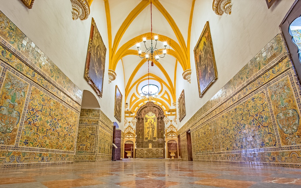 Interior of Alcazar of Seville with ornate tiles and vaulted ceiling.