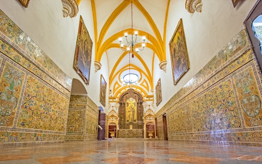 Interior of Alcazar of Seville with ornate tiles and vaulted ceiling.