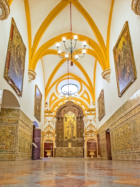 Interior of Alcazar of Seville with ornate tiles and vaulted ceiling.