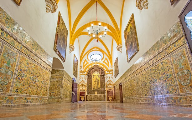 Interior of Alcazar of Seville with ornate tiles and vaulted ceiling.