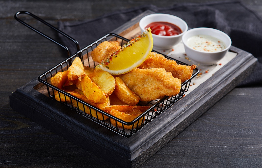 Traditional British fish and chips served on a wooden board in Belfast.