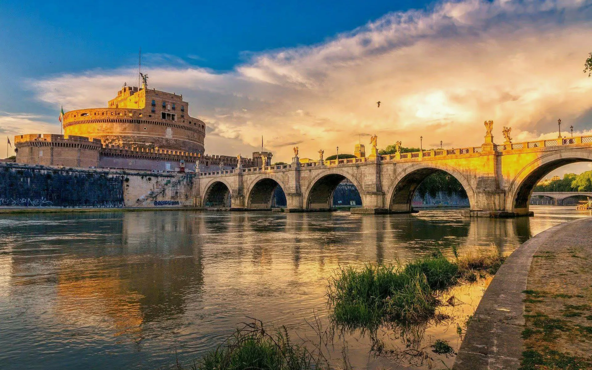 Castel Sant'Angelo and Ponte Sant'Angelo over the Tiber River at sunset in Rome.