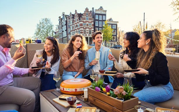 Group enjoying cheese and wine on a luxury flower boat cruise in Amsterdam canals.