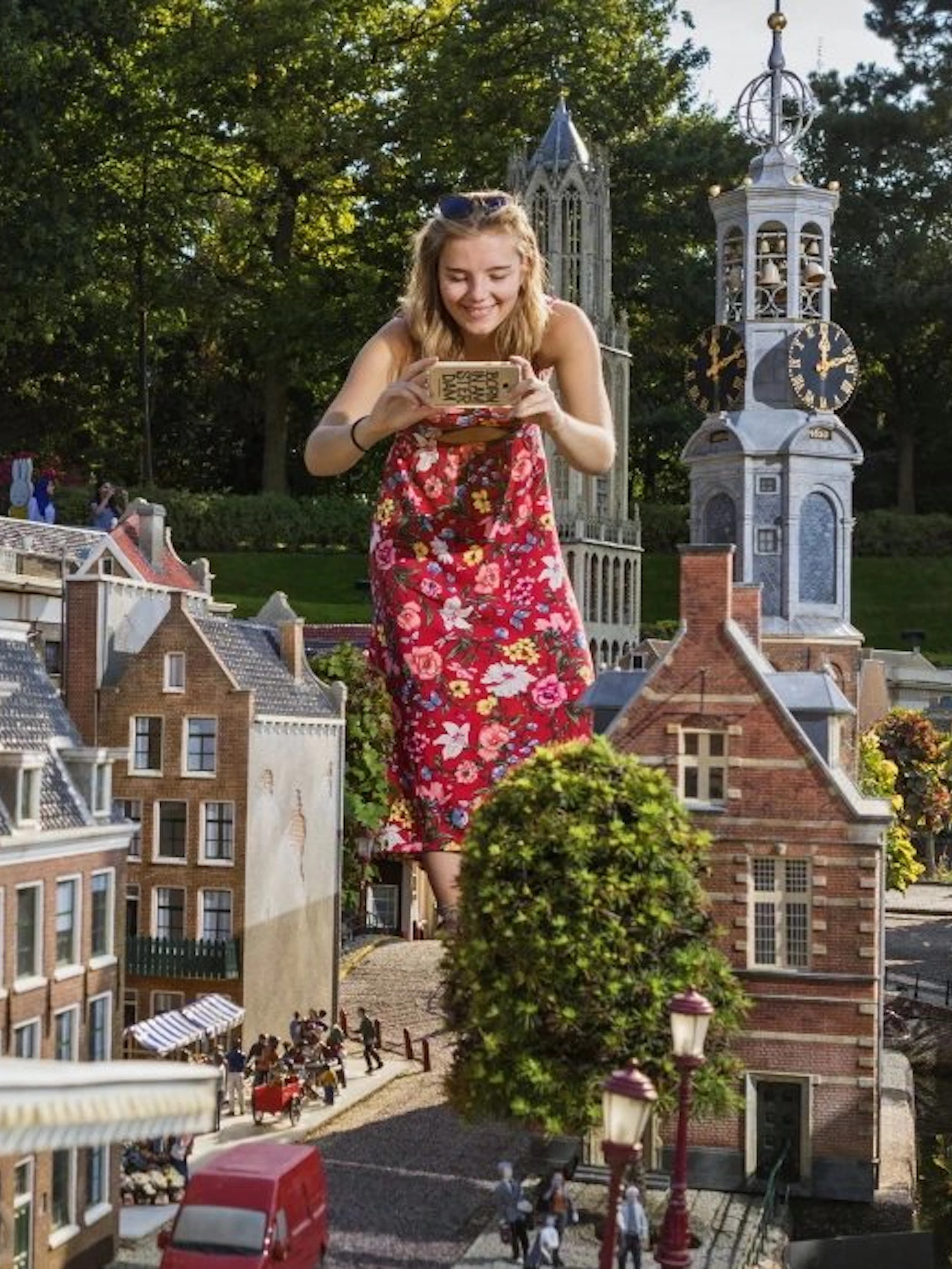 Woman photographing miniature Dutch buildings at Madurodam park.