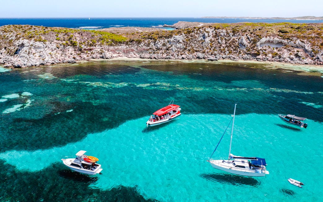 Snorkel tour boats in turquoise waters near rocky coastline, Perth/Fremantle.