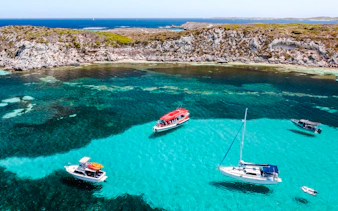Snorkel tour boats in turquoise waters near rocky coastline, Perth/Fremantle.