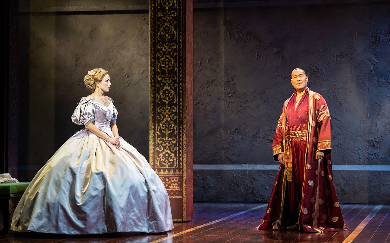 Stage scene from "The King and I" with two actors in period costumes.