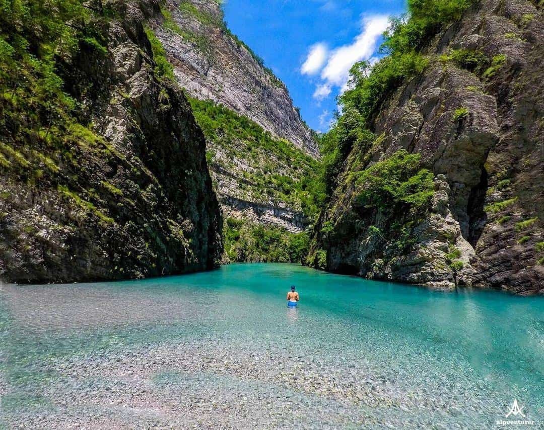 Guest swimming in clear waters of Komani Lake surrounded by rocky cliffs during Tirana day trip.