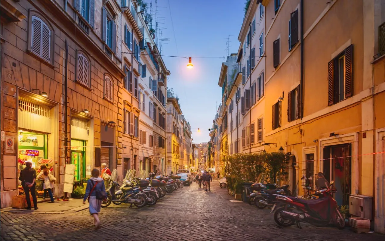 Evening street scene in Rome with people walking and scooters parked, part of Ghosts of Rome tour.