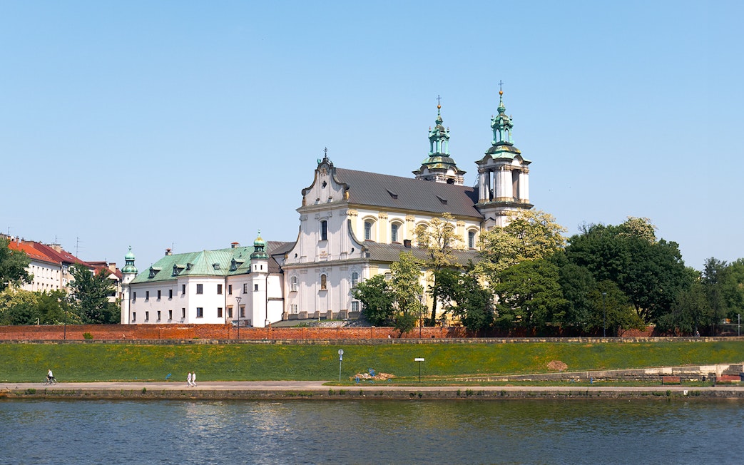 Vistula River cruise view of historic church and greenery in Krakow, Poland.
