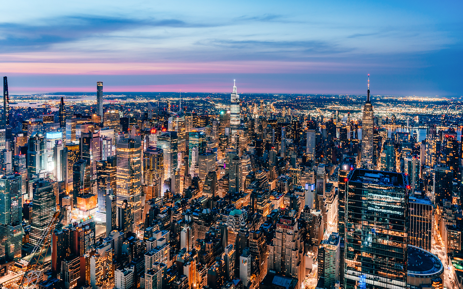 Aerial view of New York City skyline at dusk, highlighting skyscrapers and city lights.