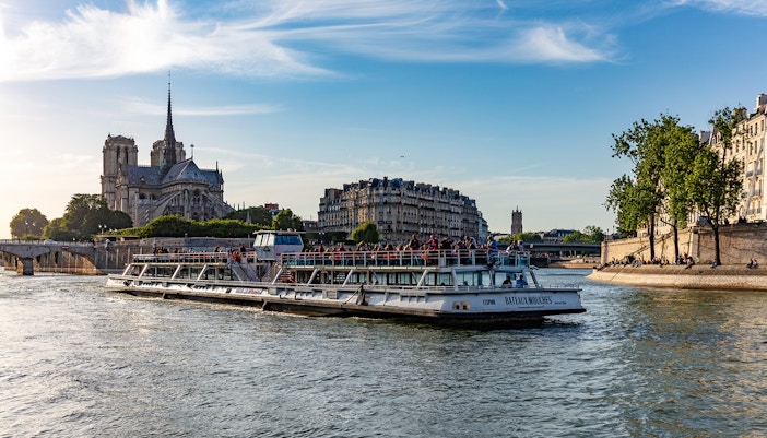 Passengers enjoying a Seine River Sightseeing Cruise with Champagne, viewing Paris landmarks from a Bateaux Mouches boat