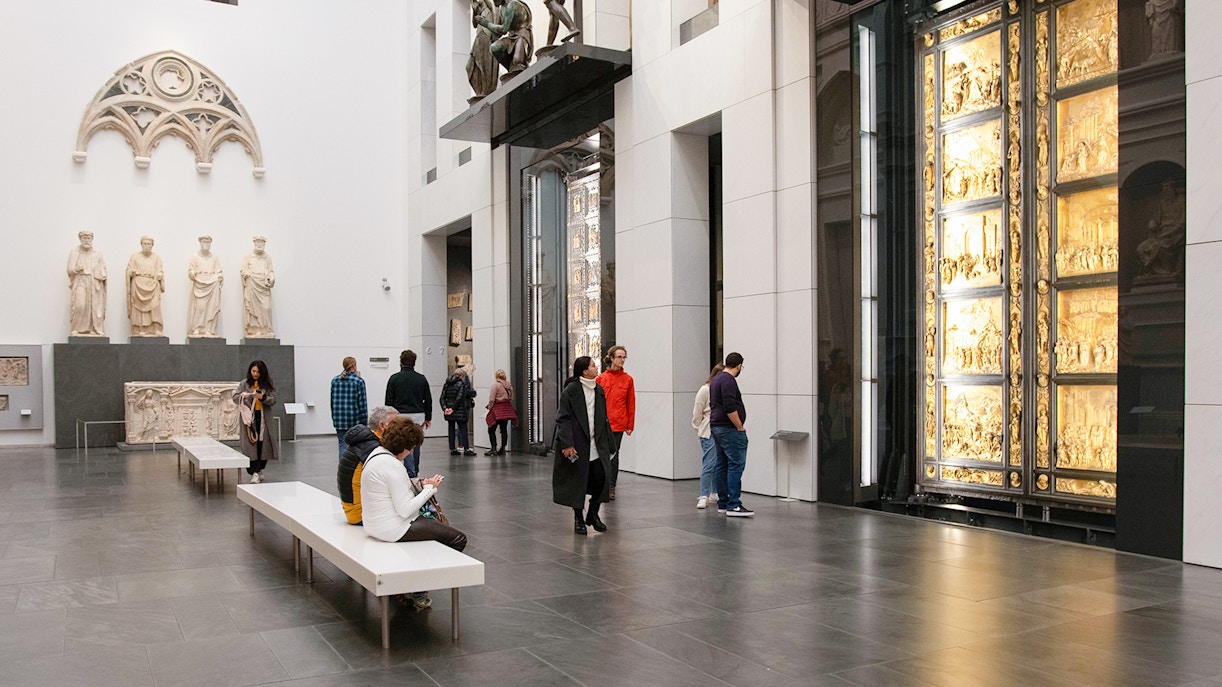 Visitors at Opera del Duomo Museum in Florence, viewing Giotto's Bell Tower and nearby monuments.